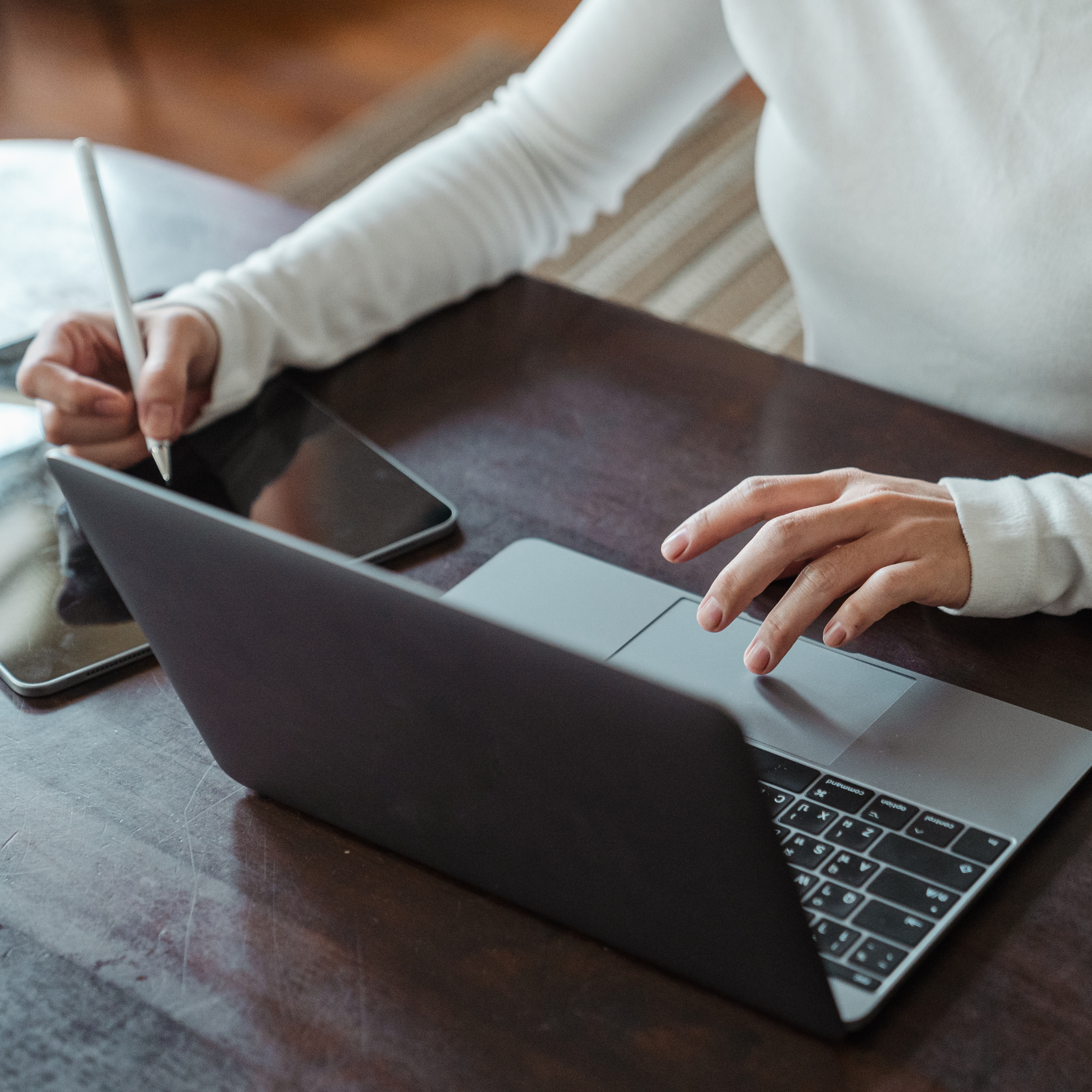 Mains sur un ordinateur portable, un stylet à la main